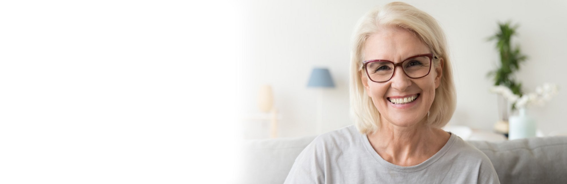 Blonde Frau mit roter Brille lächelt in Kamera